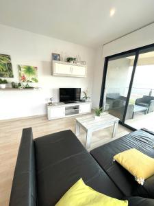 ein Wohnzimmer mit einer schwarzen Couch und einem Fernseher in der Unterkunft Luxury and Modern Beach Apartment with Sea Views in La Mata