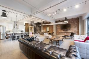 a large living room with a leather couch and a kitchen at The Holland Hotel by Simplissimmo in Montréal