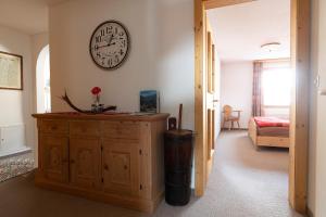 a room with a clock on the wall and a wooden cabinet at Chasa Grusaida, Vulpera in Vulpera