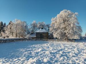 um campo coberto de neve com um edifício ao fundo em "LA MAIN D'OR " avec espaces Sauna et salle de Sport em Spa