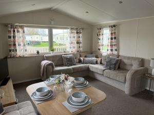 a living room with a couch and a table at Modern, Spacious 2 bedroom caravan - Thorpe Park Haven, Cleethorpes in Cleethorpes