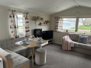 ein Wohnzimmer mit einem Sofa und einem Tisch in der Unterkunft Modern, Spacious 2 bedroom caravan - Thorpe Park Haven, Cleethorpes in Cleethorpes