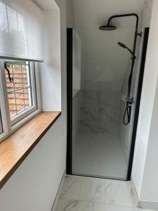 a glass shower in a room with a window at Stylish Surrey Hills House 2 ensuite bedrooms in Ockley