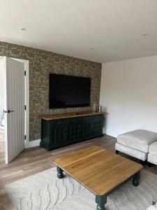 a living room with a flat screen tv on a wall at Stylish Surrey Hills House 2 ensuite bedrooms in Ockley