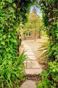 a garden path with a fence and a house at Brook Cottage in Kelling