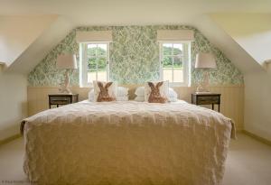 a bedroom with a large bed with two windows at Brook Cottage in Kelling