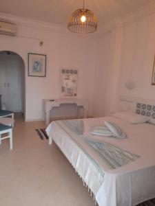 a white bedroom with a bed and a desk at DAR BELDI in Hammamet