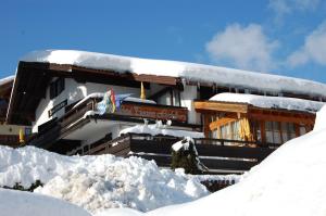 a building covered in snow with a pile of snow at Hotel - Pension - Heidelberg in Ruhpolding