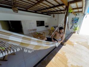 a man sitting in a hammock in a house at Barra Grande Pousada in Maragogi