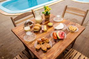 a wooden table with breakfast foods and milk on it at Barra Grande Pousada in Maragogi