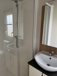 een witte badkamer met een wastafel en een douche bij Modern, Spacious 2 bedroom caravan - Thorpe Park Haven, Cleethorpes in Cleethorpes