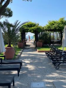 une rangée de bancs avec des parasols et la plage dans l'établissement Hotel Viña del Mar Pineta, à Lido di Jesolo