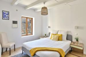 - une chambre blanche avec un lit et une chaise dans l'établissement Appartement Eglise Notre-Dame-des-Calades, à Villefranche-sur-Saône
