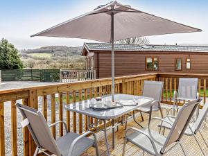 una mesa y sillas con una sombrilla en la cubierta en 3 bed in Okehampton 82415 en Okehampton