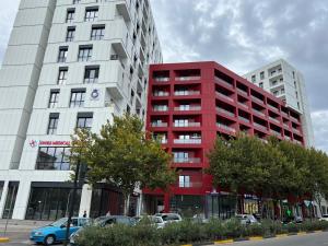 a red apartment building with cars parked in front of it at Urbanin Apartment & Hotel in Tirana