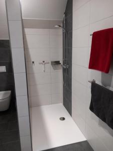 ein Bad mit einer Dusche und einem roten Handtuch in der Unterkunft Neubau: Ferienwohnung Im Suddenfeld - zentral und doch ruhig gelegen in Nordhorn