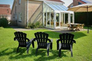 three chairs and a table in a yard with a greenhouse at Hello Zeeland - Vakantiehuis Schelde 148 in Breskens