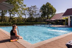 une femme assise au bord d'une piscine dans l'établissement Summio Parc Duc de Brabant, à Westelbeers