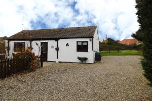 a small white house with a gravel driveway at Paddock Bungalow in Mundesley
