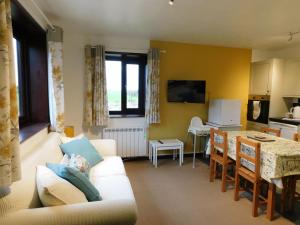 a living room with a white couch and a kitchen at Paddock Bungalow in Mundesley