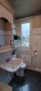 La salle de bains est pourvue d'un lavabo, de toilettes et d'une fenêtre. dans l'établissement Komfortables und sauberes Zimmer, à Leipzig