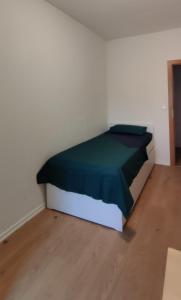 uma cama num quarto branco com um cobertor verde em Komfortables und sauberes Zimmer em Leipzig