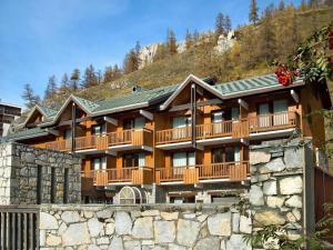 a large resort building with a stone wall at Residence & Spa Les Chalets de Solaise in Val dʼIsère