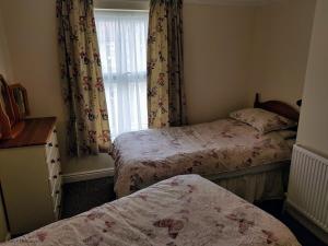 une petite chambre avec deux lits et une fenêtre dans l'établissement Old Schoolyard Cottage, à Sheringham