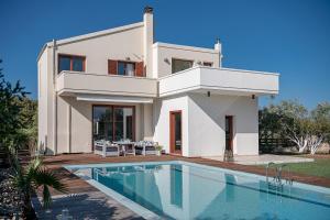 una casa blanca con piscina frente a ella en Villa Magia en Galangádhos