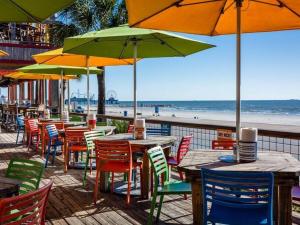 un grupo de mesas y sillas con sombrillas en una playa en The Q Loft Galveston en Galveston