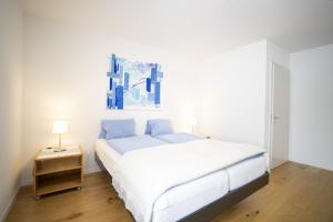 1 dormitorio con 1 cama blanca y una pintura azul en la pared en Feriensiedlung Trü 9 en Scuol