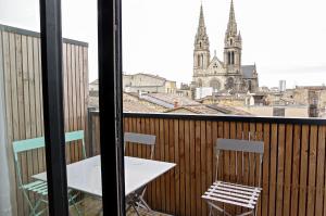 un tavolo e sedie su un balcone con vista su una chiesa di Belle Vue - Appartement 2 chambres avec parking a Bordeaux