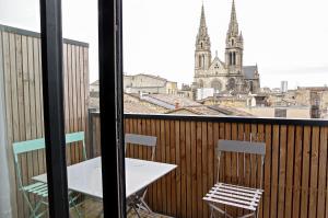 a table and chairs on a balcony with a view of a church at Belle Vue - Appartement 2 chambres avec parking in Bordeaux