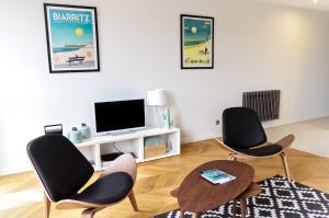 a living room with two chairs and a tv at Belle Vue - Appartement 2 chambres avec parking in Bordeaux