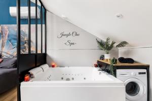 eine weiße Badewanne in einem Zimmer mit einer Waschmaschine in der Unterkunft Jungle Chic & Spa in Bourgoin