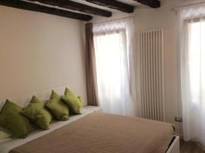 a bedroom with a bed with green pillows and a window at Nel Cuore Di Venezia in Venice