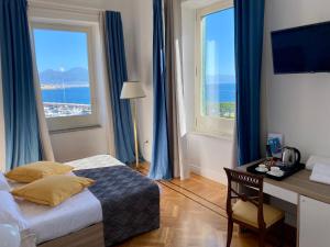 - une chambre avec un bureau et un lit avec des rideaux bleus dans l'établissement Palazzo Mele Residence, à Naples