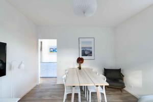 a white dining room with a table and chairs at Holiday Apartment At Beautiful Solgaarden 8 in Svaneke