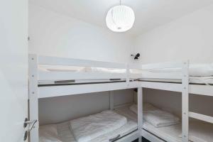 a room with white bunk beds with a light at Holiday Apartment At Beautiful Solgaarden 8 in Svaneke