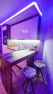 eine Küche mit violetter Beleuchtung und einer Theke mit zwei Stühlen in der Unterkunft Ginko sobe Daruvar in Daruvar
