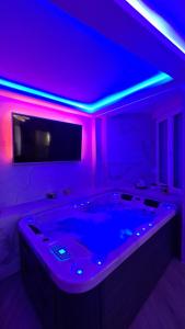 Zimmer mit einer Badewanne, einem TV und violetten Lichtern in der Unterkunft Ginko sobe Daruvar in Daruvar