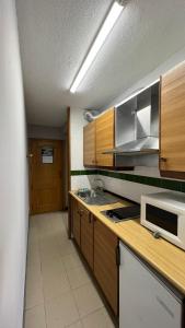 a kitchen with wooden cabinets and a sink and a microwave at Apartaments Crest Pas in Pas de la Casa
