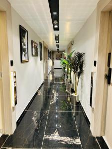 a hallway with a black tiled floor with plants at Hotel Marigold Naroda in Ahmedabad