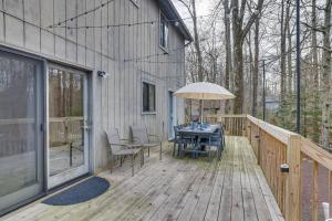 a wooden deck with a table and an umbrella at Peaceful Pocono Pines Getaway Hot Tub and Fire Pit! in Pocono Pines