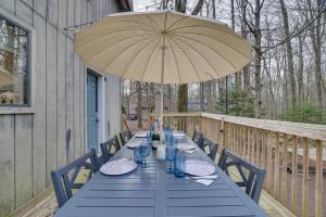 a blue table with an umbrella on a deck at Peaceful Pocono Pines Getaway Hot Tub and Fire Pit! in Pocono Pines