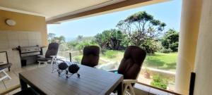 a dining room with a table and a large window at Shelly Beach beachfront apartment in Shelly Beach