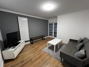 a living room with a couch and a tv at Springfield House- Near Newcastle Centre, Hospital and Keele University! in Stoke on Trent