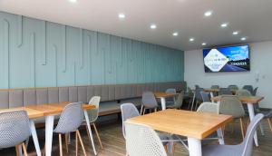 a dining room with tables and chairs and a screen at Hotel Bacata Plaza in Zipaquirá