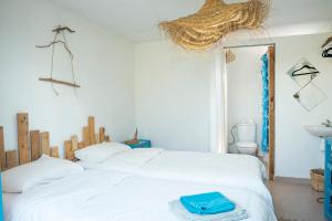 um quarto com uma cama branca e uma toalha azul em Satya Surf Camp em Tamaris