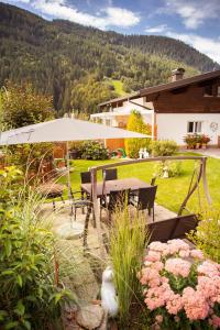 a patio with a table and an umbrella and flowers at Alpenstern Apartment Montafon in Sankt Gallenkirch